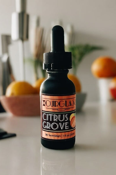 OURGLASS Citrus Grove delta 9 tincture bottle on a kitchen counter with fresh fruits, showcasing thc tincture for an active lifestyle.