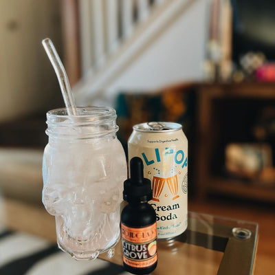 OURGLASS Citrus Grove Delta-9 THC drops, paired with a refreshing OLIPOP Cream Soda for a delightful and unique beverage experience.