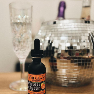 OURGLASS Delta-9 drops for drinks displayed with a crystal glass and disco ball, ideal for creating Delta-9 beverages and thc tincture cocktails.